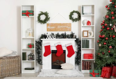 İçinde Noel çelenkleri, şömine ve raf üniteleri olan oturma odası.