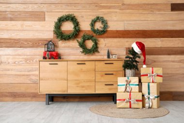 Oturma odasının içinde Noel ağacı, çekmece ve çelenkler var.