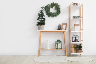 İçinde Noel çelengi, masa ve raf ünitesi olan oturma odası.