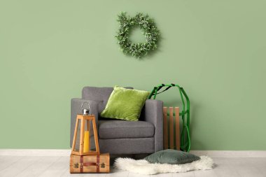 Kızaklı koltuk ve yeşil duvarın yanındaki bavulda Noel feneri.