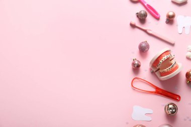 Pembe arka planda dişçi aletleri, kağıt dişler ve Noel süslemeleri olan kompozisyon