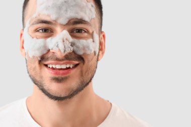 Yüzünde kozmetik balon maskesi olan yakışıklı, genç ve mutlu bir adam.