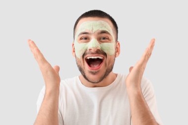 Yüzünde kozmetik balon maskesi olan yakışıklı, genç ve şaşkın bir adam.