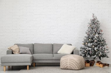 Hediye kutularıyla süslenmiş Noel ağacı, oturma odasının içindeki kanepe.