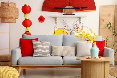 Oturma odasının içinde gri kanepe ve Çin Yeni Yıl kutlamaları için süslemeler var.