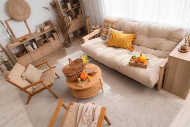 Sonbahar dekoru, kanepesi ve koltuğu olan bir oturma odası.