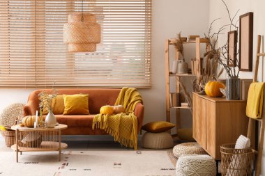 Turuncu kanepe, balkabağı, çekmece sandığı ve sonbaharda oturma odasının içinde kahve masası.