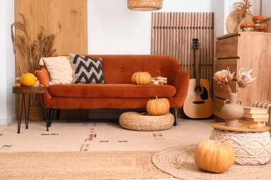 Rahat bir kanepe, balkabağı, akustik gitar ve sonbaharda oturma odasının iç kısımlarında kahve masası.