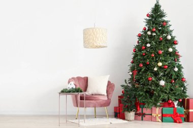 İçinde pembe koltuk, Noel ağacı ve hediye kutuları olan şenlikli bir oturma odası.