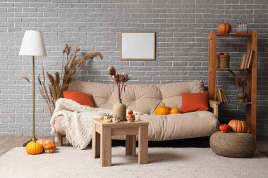 Sonbahar dekoru, kanepesi ve masası olan modern oturma odasının içinde.