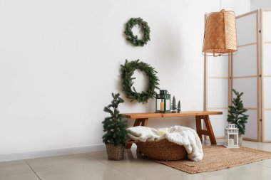 Oturma odasının içinde Noel ağaçları, çelenkler ve ahşap banklar var.