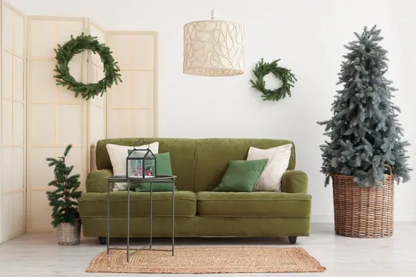 stock image Interior of festive living room with green sofa, Christmas tree and wreathes