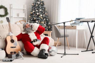Evde gitar çalan kulaklıklı Noel Baba.