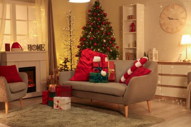 Noel Baba çantasıyla oturma odasının içi ve geceleri kanepenin üzerinde Noel hediyeleri.