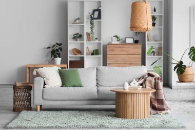 Gri kanepe, masa ve raf üniteleriyle aydınlık oturma odasının içinde.