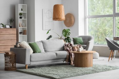 Gri kanepe, masa ve raf ünitesiyle aydınlık oturma odasının içinde.