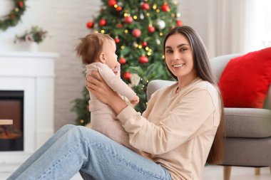 Mutlu anne ve küçük bebeği Noel arifesinde evde oturuyor.