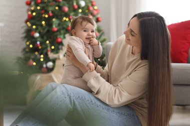 Mutlu anne ve küçük bebeği Noel arifesinde evde oturuyor.