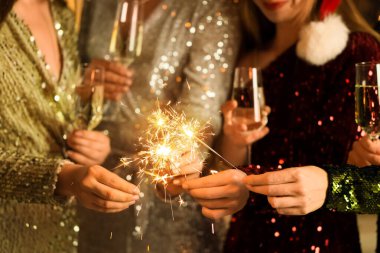 Noel partisinde şampanya ve maytap taşıyan güzel kadınlar, yakın plan.