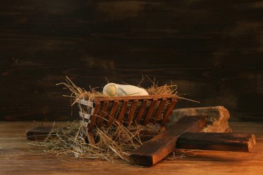 Bebekli ahır, ahşap zeminde haç ve saman. Noel hikayesi konsepti