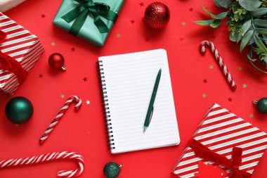 Kırmızı arka planda sunulan ve Noel dekoru olan defter