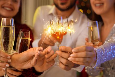 Partide şampanya ve Noel havai fişeği olan insanlar, yakın plan.