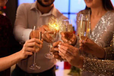 Partide şampanya ve Noel havai fişeği taşıyan gençler, yakın plan.