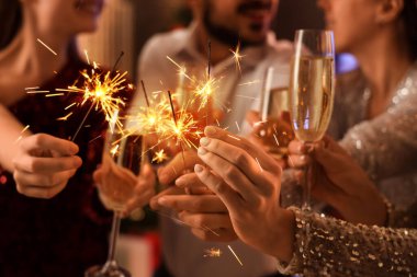 Partide şampanya ve Noel havai fişeği taşıyan gençler, yakın plan.