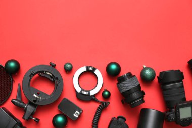 Kırmızı arka planda Noel topları olan fotoğrafçı ekipmanları.