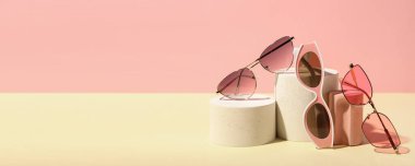 Dekoratif podyumlar ve renkli arkaplan üzerinde şık güneş gözlükleri ve metin için boşluk