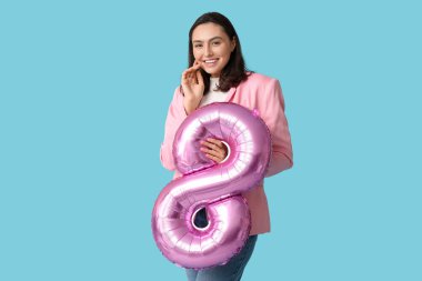 Mavi arka planda 8 şeklinde pembe hava balonu olan güzel genç bir kadın. Uluslararası Kadınlar Günü