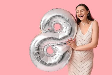 Pembe arka planda 8 şeklinde gümüş renkli balonu olan mutlu genç bir kadın. Uluslararası Kadınlar Günü