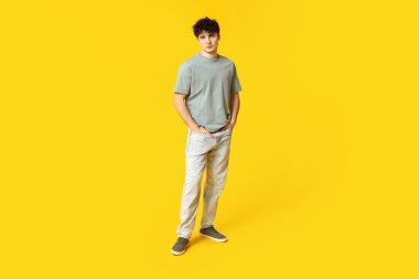 Sarı arka planda şık giyinmiş yakışıklı bir genç.