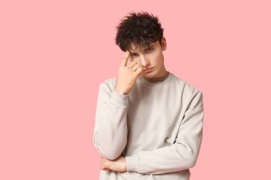 Pembe arka planda şık bir kazak giyen yakışıklı genç adam.