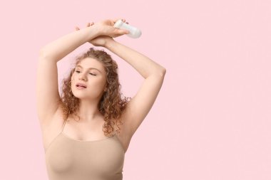 Pembe arka planda deodorantı olan güzel bir kadın.