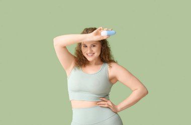 Yeşil arka planda deodorantı olan güzel genç bir kadın.