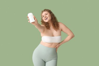 Yeşil arka planda deodorantı olan mutlu genç bir kadın.
