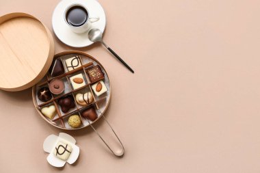 Lezzetli çikolata şekerlemeleri, mutfak maşaları, kahverengi arka planda bir fincan kahve ve kaşık.