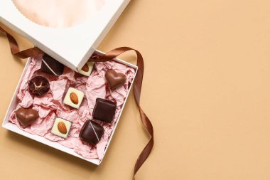 Kahverengi arka planda lezzetli çikolata şekerleriyle dolu bir kutu.