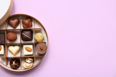 Leylak arkaplanda lezzetli çikolata şekerleriyle dolu bir kutu.