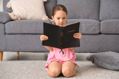 Evinde yerde İncil okuyan tatlı küçük kız.