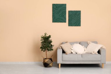 Oturma odasının iç tarafında rahat bir kanepe ve çiçek var.