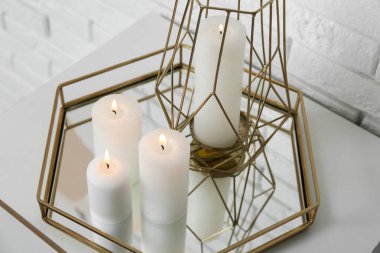 Oturma odasındaki beyaz tuğla duvarın yanındaki dolapta mum yakmak, yakın çekim.