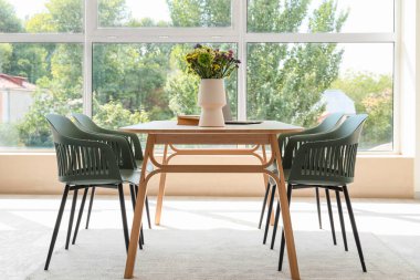 Yemek masasının üstünde kır çiçekleri ve dizüstü bilgisayarlı vazo.