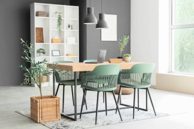 Yemek odasının içinde masa, raf ünitesi ve bitkiler var.