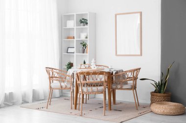 Masası, hasır sandalyeleri ve beyaz duvarın yanındaki raf ünitesi olan yemek odasının içinde.