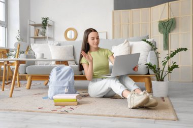 Evde dizüstü bilgisayarı olan bir kız öğrenci sohbet ediyor.