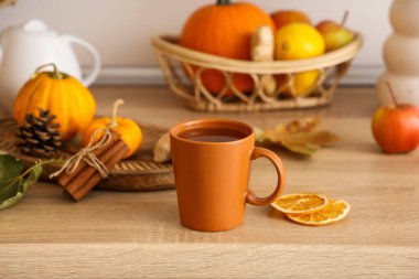 Bir fincan sıcak yeşil çay, balkabağı, kurutulmuş portakal dilimleri ve mutfak masasındaki ahşap tepsi.