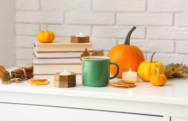 Bir kupa lezzetli yeşil çay, mumlar, kitaplar ve masada kurutulmuş portakal dilimleri.