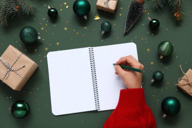 2025 yılını Noel dekoru ve yeşil arka planda hediyelerle geçiren bir kadın.